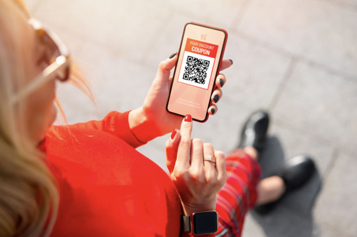 Image of a woman using a mobile device to interact with a loyalty program, with personalized offers and rewards displayed on the screen. The image highlights the importance of customer engagement in loyalty programs and how personalization can improve customer loyalty and retention rates.